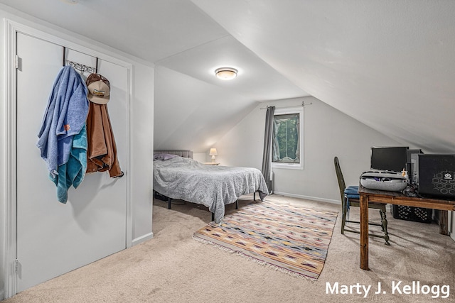 carpeted bedroom featuring vaulted ceiling, a desk, and baseboards