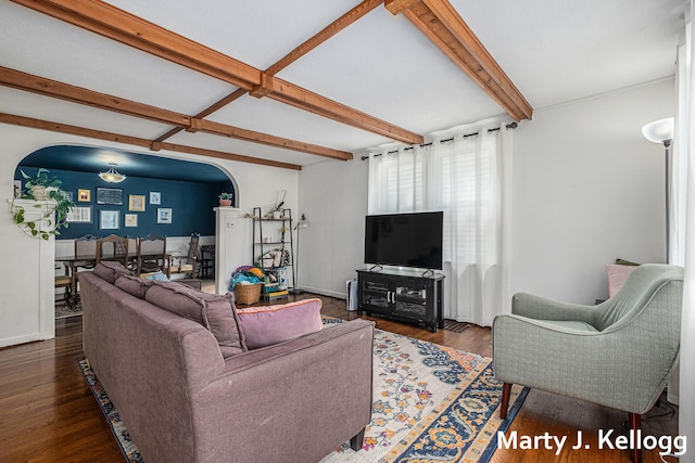 living area with arched walkways, beamed ceiling, wood finished floors, and baseboards