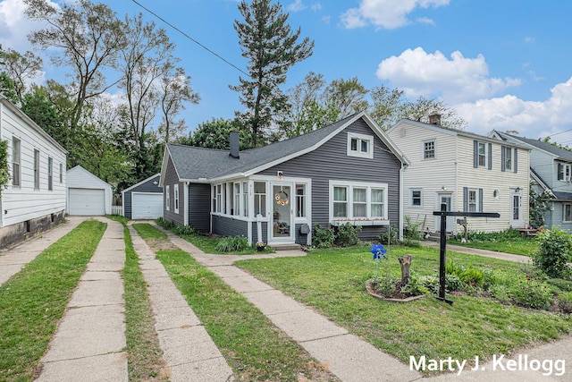 view of front of property featuring a detached garage, a front yard, a chimney, driveway, and an outdoor structure