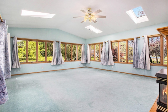 carpeted empty room featuring a skylight, lofted ceiling, baseboards, and a ceiling fan