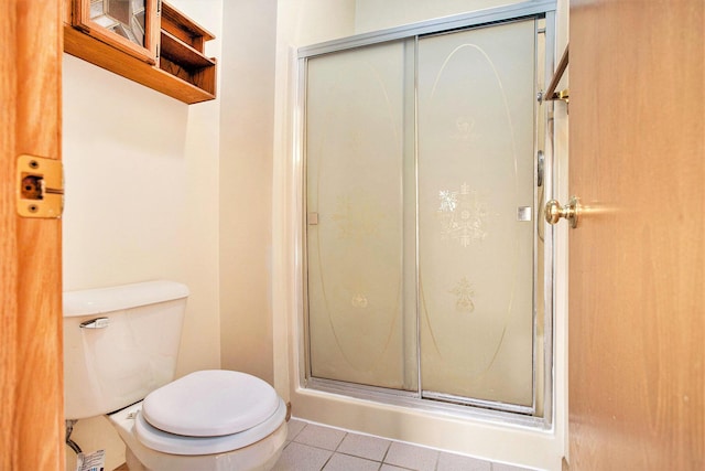 bathroom with a shower stall, tile patterned flooring, and toilet