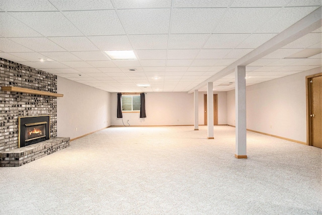 finished below grade area with carpet flooring, a fireplace, a paneled ceiling, and baseboards