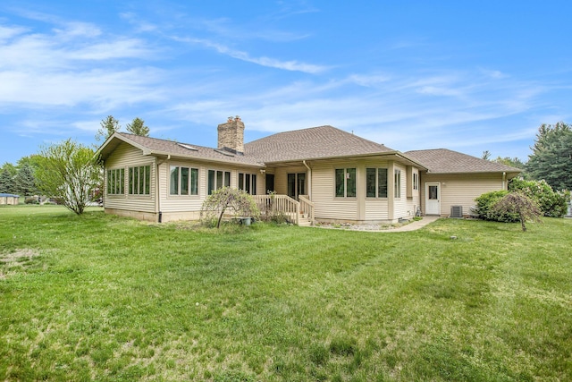 rear view of property featuring a chimney, a yard, and roof with shingles