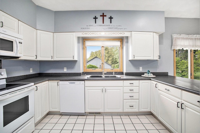 kitchen with white appliances, a sink, dark countertops, white cabinets, and light tile patterned flooring