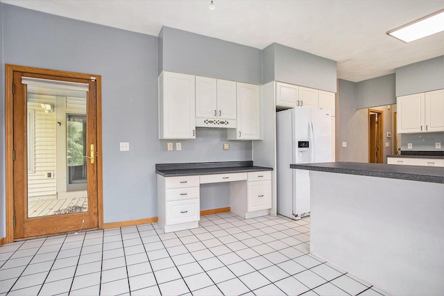 kitchen with white fridge with ice dispenser, dark countertops, white cabinetry, and baseboards