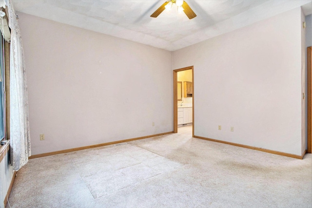 spare room with light colored carpet, a ceiling fan, and baseboards