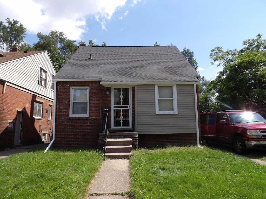 20136 Hull St, Detroit, MI 48203 - bungalow with a front yard, entry steps, roof with shingles, and brick siding