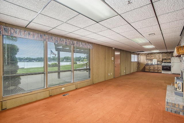 10706 Portage Rd, Portage, MI 49002 - basement with light colored carpet, freestanding refrigerator, a wood stove, a drop ceiling, and wooden walls