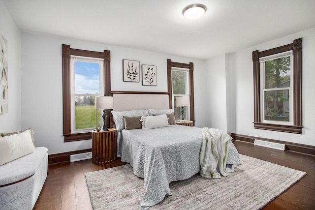 bedroom with multiple windows, hardwood / wood-style floors, and baseboards