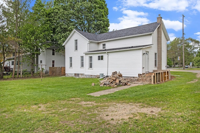 back of house featuring a chimney and roof with shingles