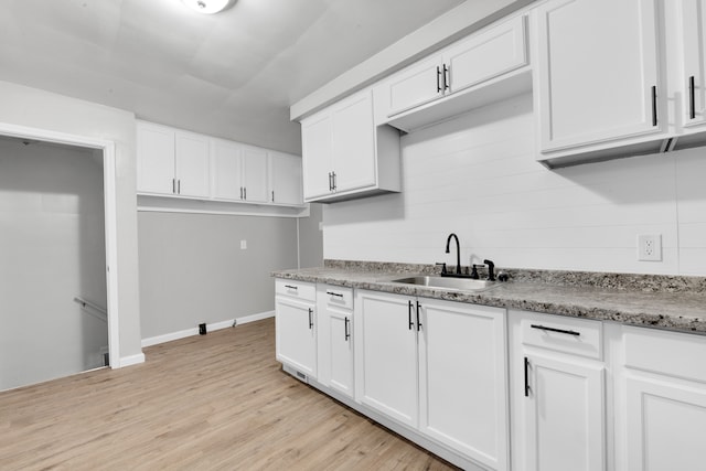 15819 Eastburn St, Detroit, MI 48205 - kitchen featuring a sink, light wood-style floors, white cabinets, baseboards, and light stone countertops