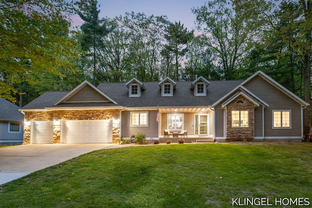 view of front of home with stone siding, concrete driveway, a front lawn, and an attached garage