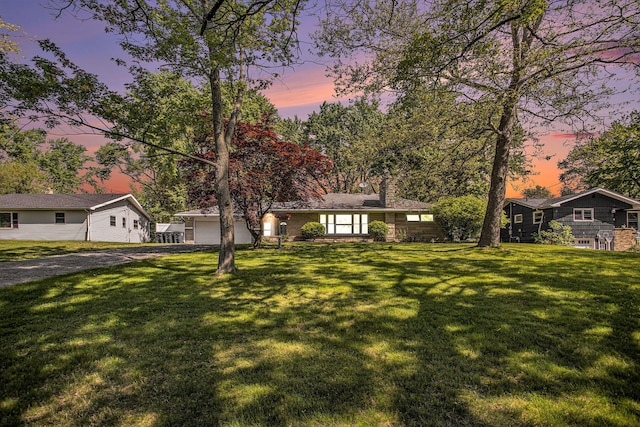 view of front of home featuring driveway, a chimney, a front yard, and a garage