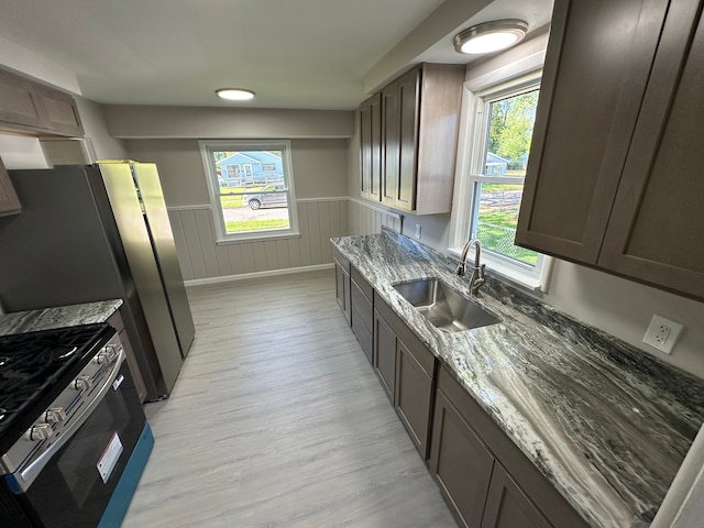 92 W Princeton Ave, Pontiac, MI 48340 - kitchen featuring a sink, stainless steel gas range, light wood-style floors, stone countertops, and a wainscoted wall