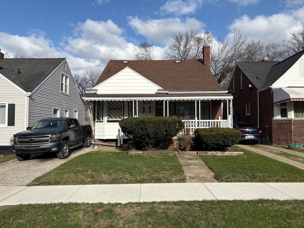 19366 Mansfield St, Detroit, MI 48235 - bungalow-style home with covered porch, a front yard, a chimney, brick siding, and roof with shingles