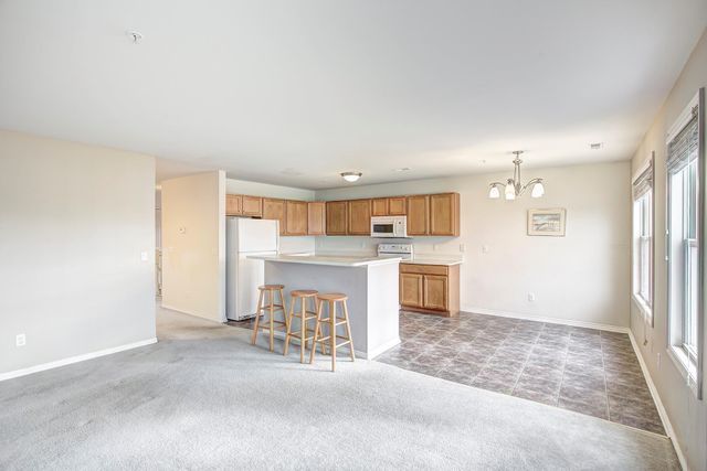 3986 Forester Blvd, Auburn Hills, MI 48326 - kitchen with white appliances, a chandelier, light countertops, baseboards, and a center island