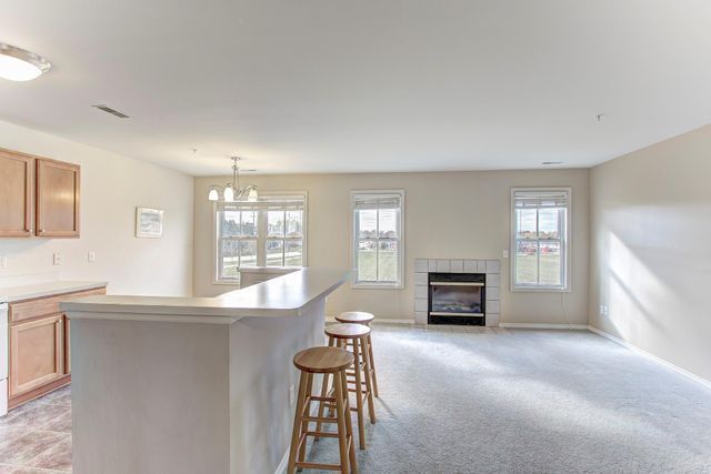 3986 Forester Blvd, Auburn Hills, MI 48326 - kitchen featuring healthy amount of natural light, a tiled fireplace, a kitchen bar, and light countertops