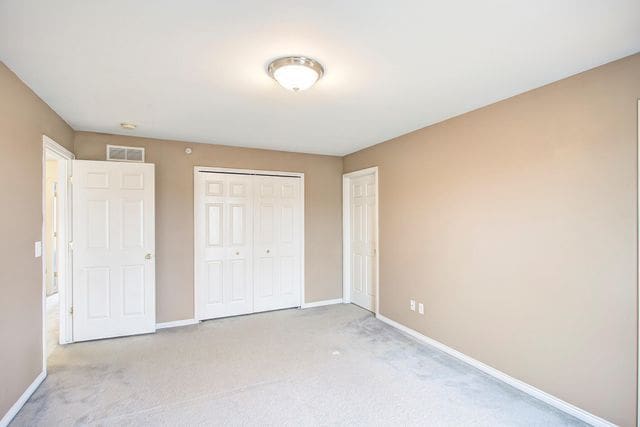 3986 Forester Blvd, Auburn Hills, MI 48326 - unfurnished bedroom with baseboards, light colored carpet, and a closet