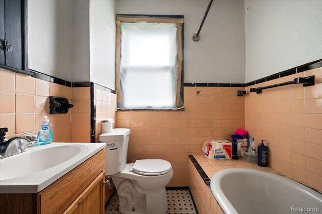 8214 Saint Marys St, Detroit, MI 48228 - bathroom with tile walls, toilet, tiled bath, vanity, and a wainscoted wall