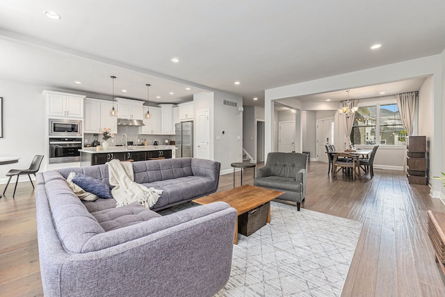 3328 Roseford Blvd, Ann Arbor, MI 48105 - living room with wood-type flooring, a chandelier, recessed lighting, baseboards, and stairs