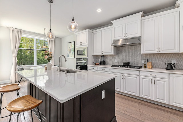 3328 Roseford Blvd, Ann Arbor, MI 48105 - kitchen featuring under cabinet range hood, appliances with stainless steel finishes, light wood finished floors, decorative backsplash, and light countertops