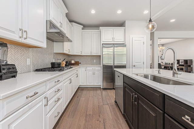 3328 Roseford Blvd, Ann Arbor, MI 48105 - kitchen with stainless steel appliances, under cabinet range hood, a sink, white cabinetry, and a chandelier