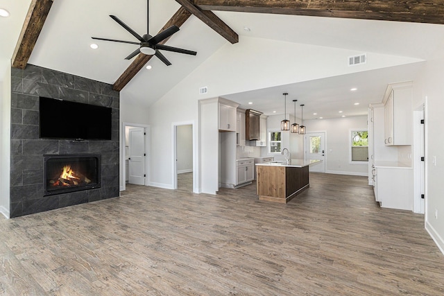 9693 Beverly Dr, Lakeland, MI 48143 - kitchen with open floor plan, wood finished floors, a center island with sink, baseboards, and beam ceiling