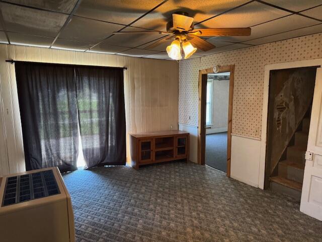empty room featuring carpet floors, a drop ceiling, and ceiling fan