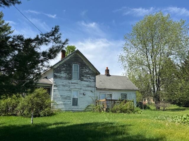 back of property featuring a chimney, a yard, and a deck