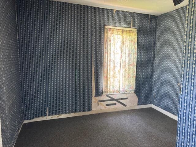 carpeted empty room featuring wallpapered walls and baseboards