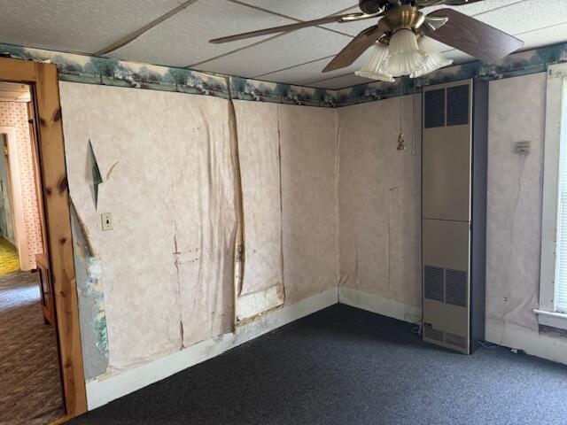 below grade area featuring a heating unit, ceiling fan, and carpet flooring
