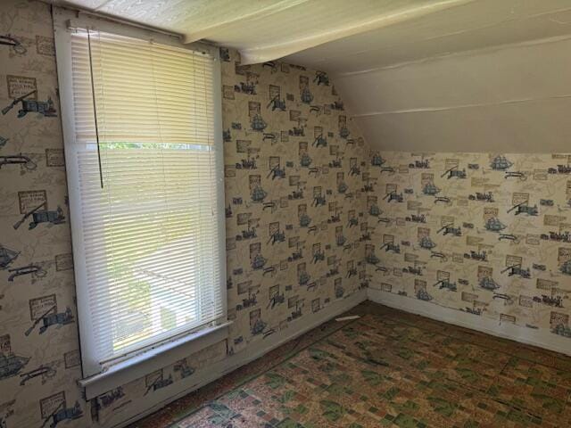 unfurnished room featuring lofted ceiling, baseboards, and wallpapered walls