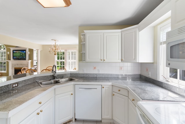 kitchen with a sink, a warm lit fireplace, tile countertops, and white cabinetry