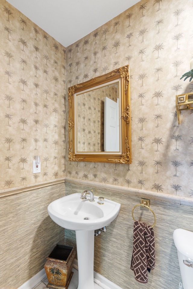 half bathroom with a wainscoted wall, toilet, and tile walls