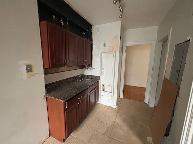 8162 E Jefferson Ave Unit 16B, Detroit, MI 48214 - kitchen with light tile patterned floors, electric panel, track lighting, dark stone counters, and baseboards