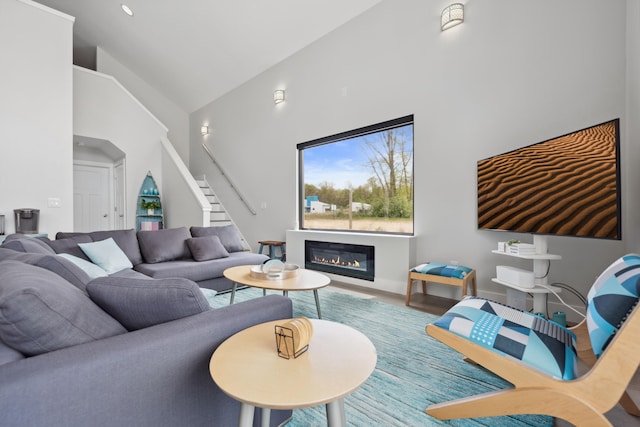 7469 Lake Solis Dr, Stevensville, MI 49127 - living room with high vaulted ceiling, stairs, a glass covered fireplace, and baseboards