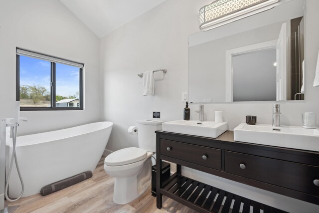 7469 Lake Solis Dr, Stevensville, MI 49127 - full bath featuring vaulted ceiling, wood finished floors, a soaking tub, toilet, and double vanity