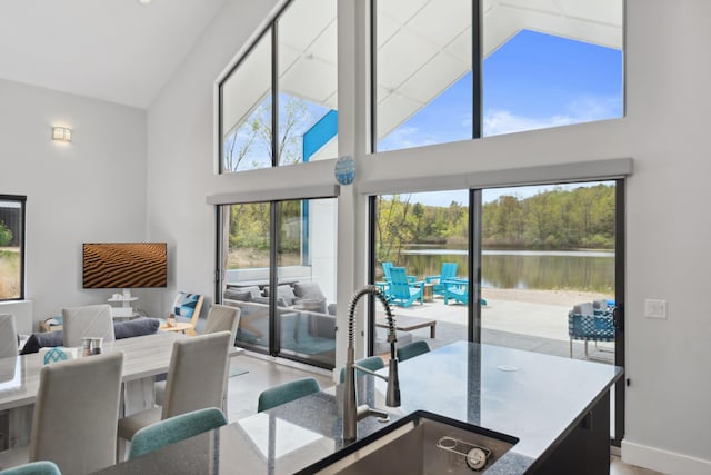 7469 Lake Solis Dr, Stevensville, MI 49127 - kitchen featuring high vaulted ceiling, a water view, open floor plan, a sink, and baseboards
