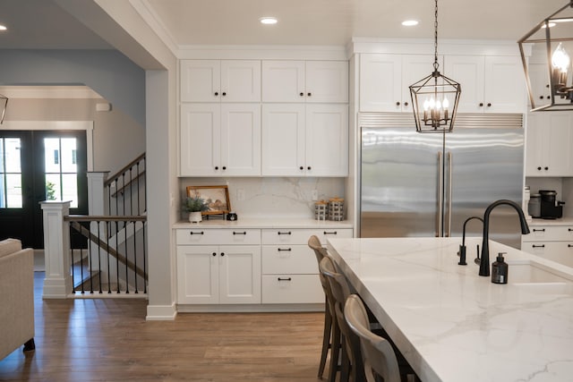 8182 Country Rail Dr SW, Byron Center, MI 49315 - kitchen with built in refrigerator, light wood finished floors, white cabinets, light stone countertops, and recessed lighting