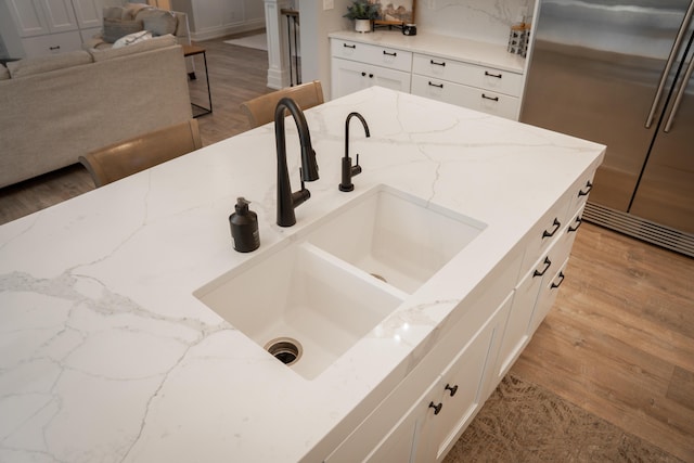 8182 Country Rail Dr SW, Byron Center, MI 49315 - detailed view of stainless steel fridge, a sink, wood finished floors, white cabinets, and light stone countertops