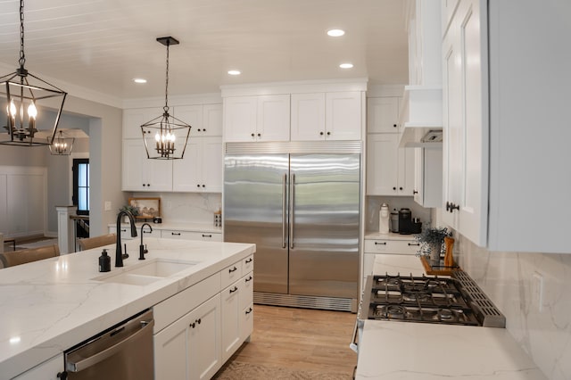 8182 Country Rail Dr SW, Byron Center, MI 49315 - kitchen featuring appliances with stainless steel finishes, a sink, a chandelier, white cabinets, and pendant lighting