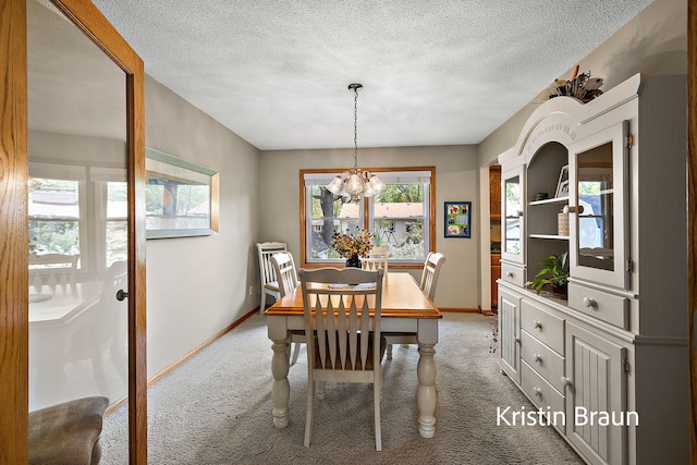 dining area featuring light colored carpet, baseboards, a chandelier, and a textured ceiling