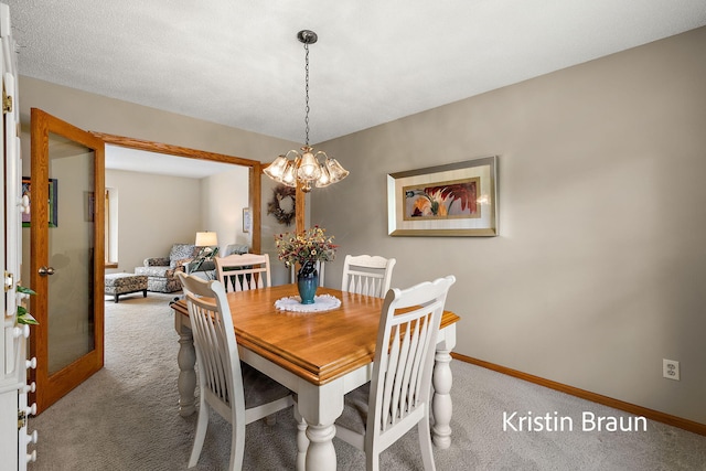 carpeted dining space featuring baseboards and a chandelier