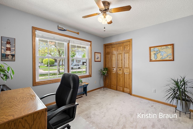 office space with ceiling fan, baseboards, light carpet, and a textured ceiling