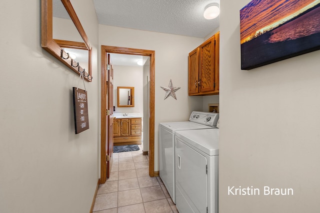 laundry area featuring cabinet space, washer and clothes dryer, light tile patterned floors, a textured ceiling, and baseboards