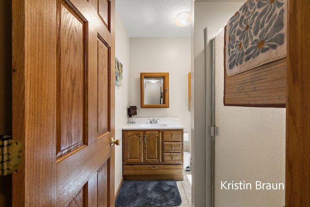 bathroom featuring vanity, tile patterned flooring, a textured ceiling, and baseboards