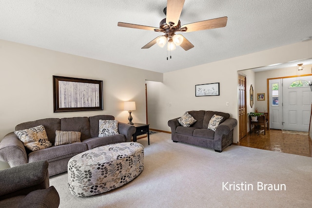 living area with carpet floors, ceiling fan, baseboards, and a textured ceiling