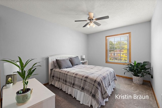 bedroom featuring dark colored carpet, baseboards, a textured ceiling, and a ceiling fan
