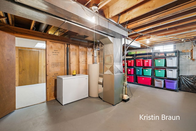 basement with refrigerator, water heater, and heating unit