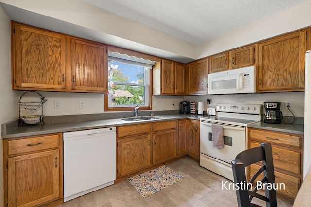 kitchen featuring white appliances, a sink, brown cabinets, and a textured ceiling